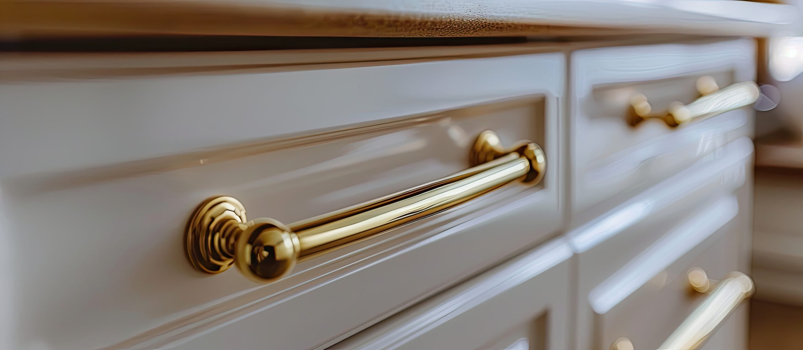 Golden furniture handle, on white wooden kitchen cabinet . Small depth of field. used as background. toned. with copy space image. Place for adding text or design
