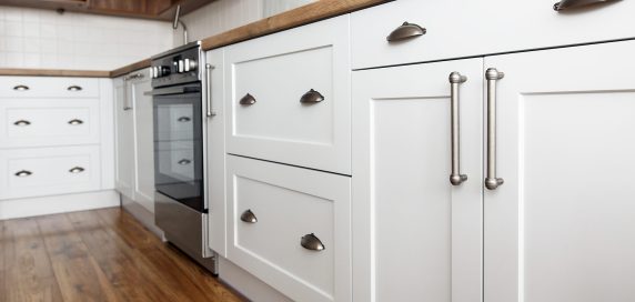 Stylish light gray handles on cabinets close-up, kitchen interior with modern furniture and stainless steel appliances. kitchen design in scandinavian style